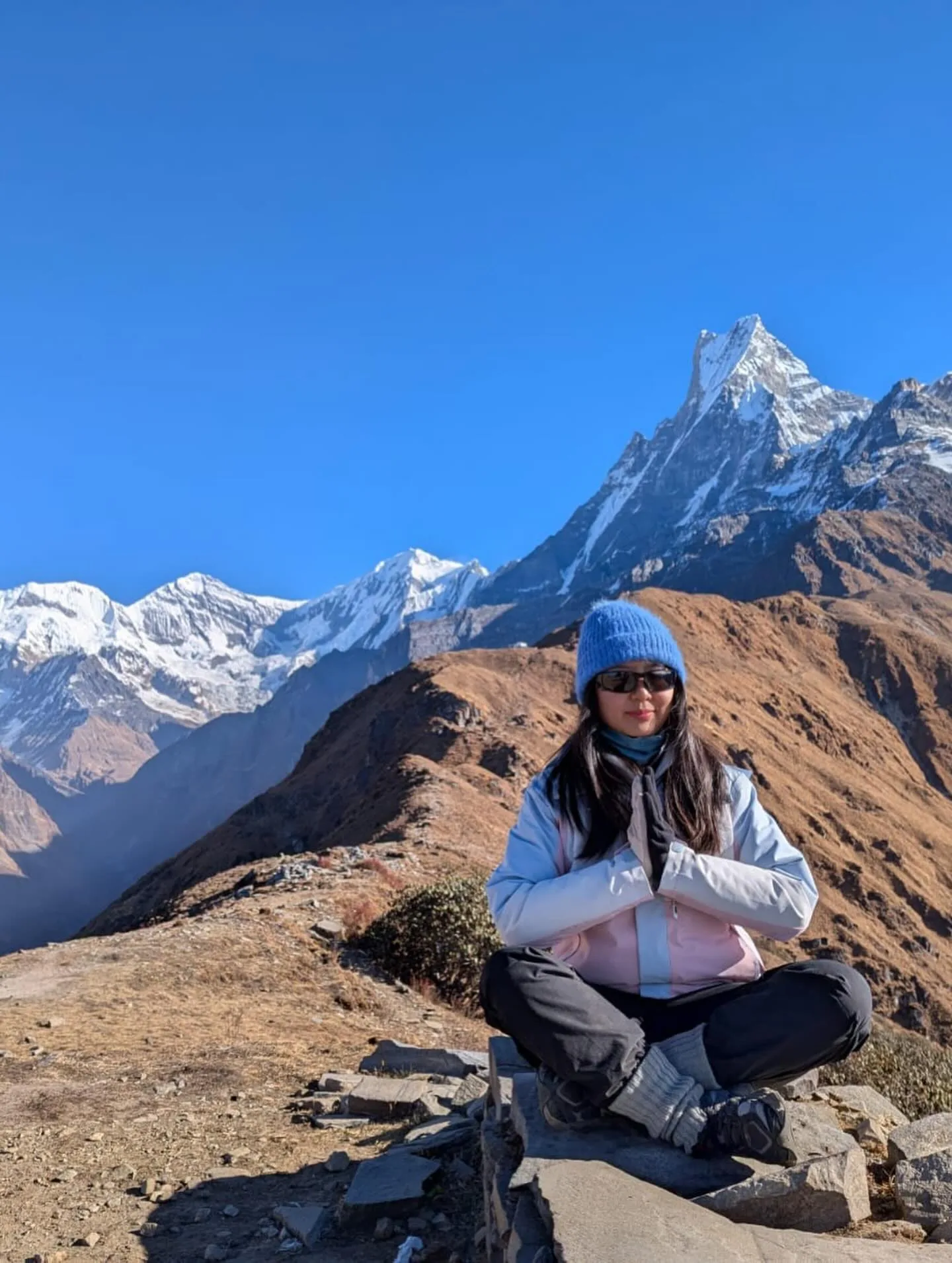 A trekker meditates on a ridge facing Machhapuchhre's fishtail summit